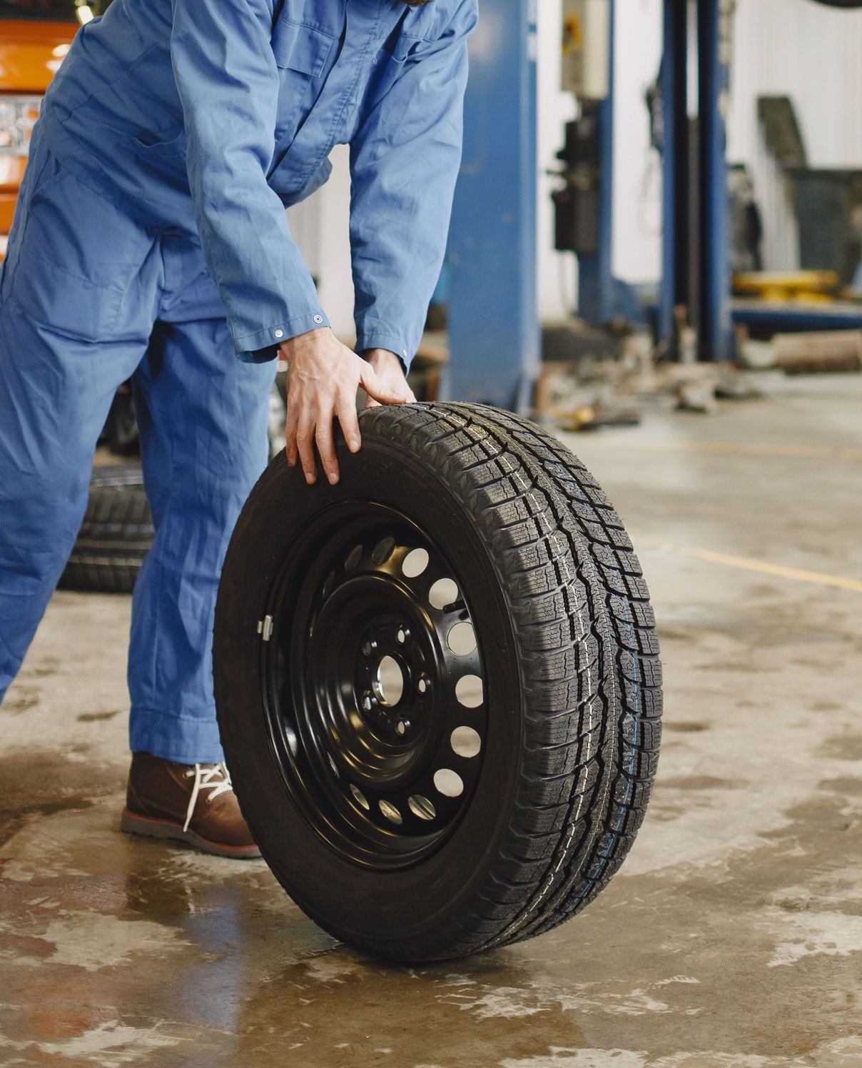 Mechanic handling a tire in a busy automotive repair workshop.